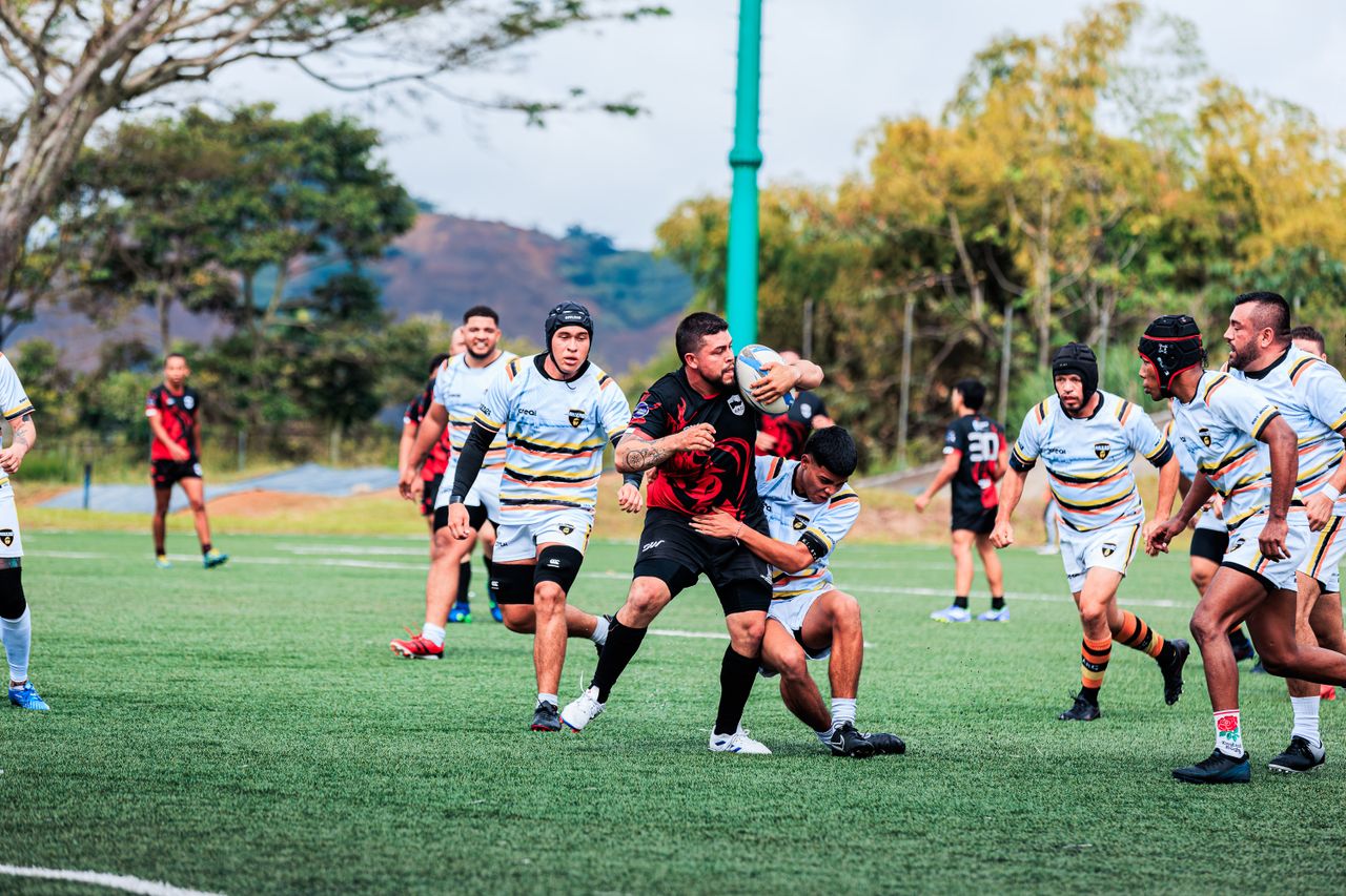 Action-packed rugby match with players tackling on a green field.